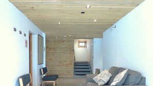 A living room with a sofa, chairs, a small table, a staircase, and a wooden ceiling. - Apart Hotel Endurance (Punta Arenas)