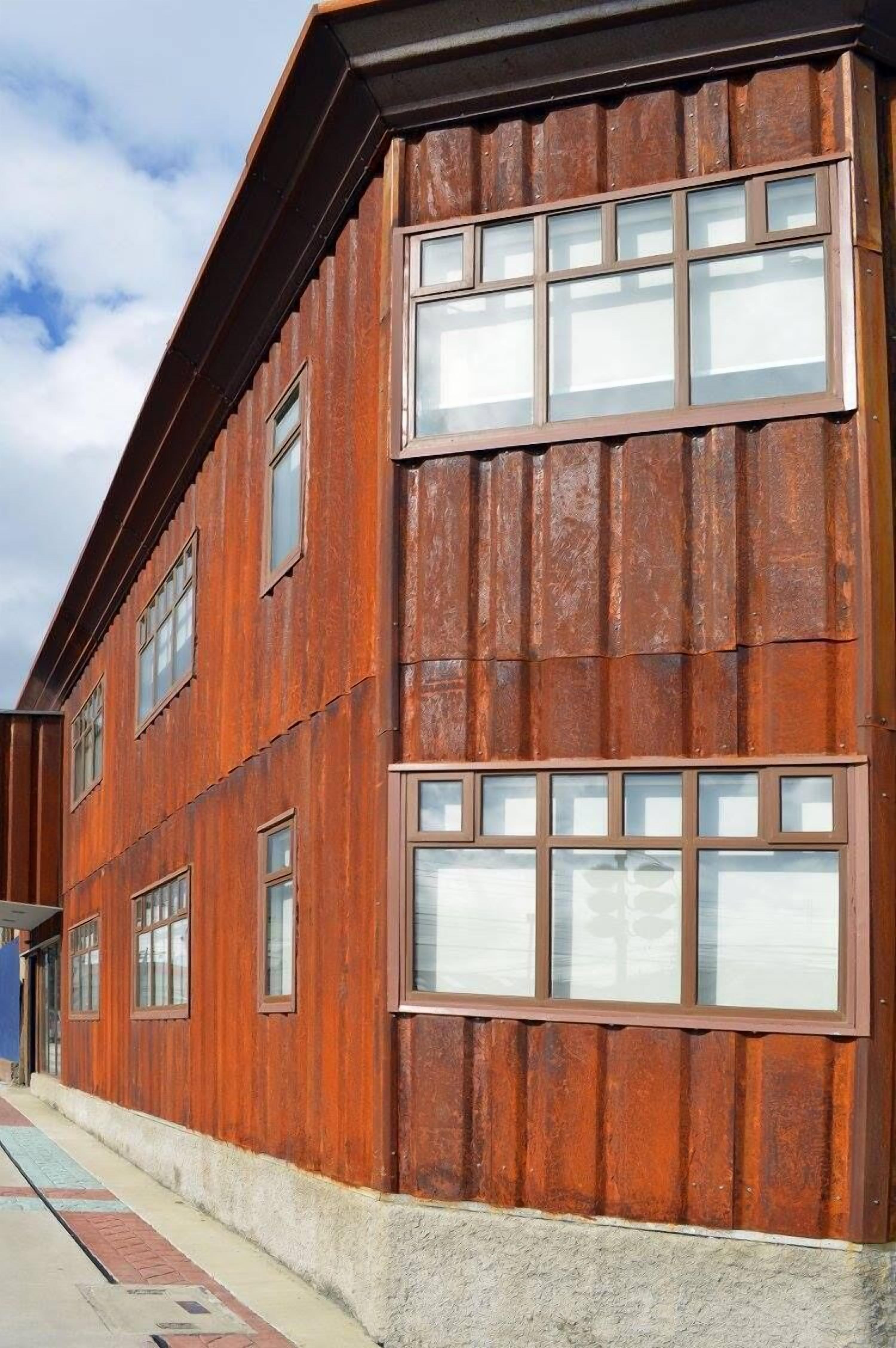 Un edificio de varios pisos con fachada rústica, caracterizado por amplias ventanas y un techo plano.