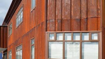 A multi-story building with a rustic exterior, featuring large windows and a flat roof.