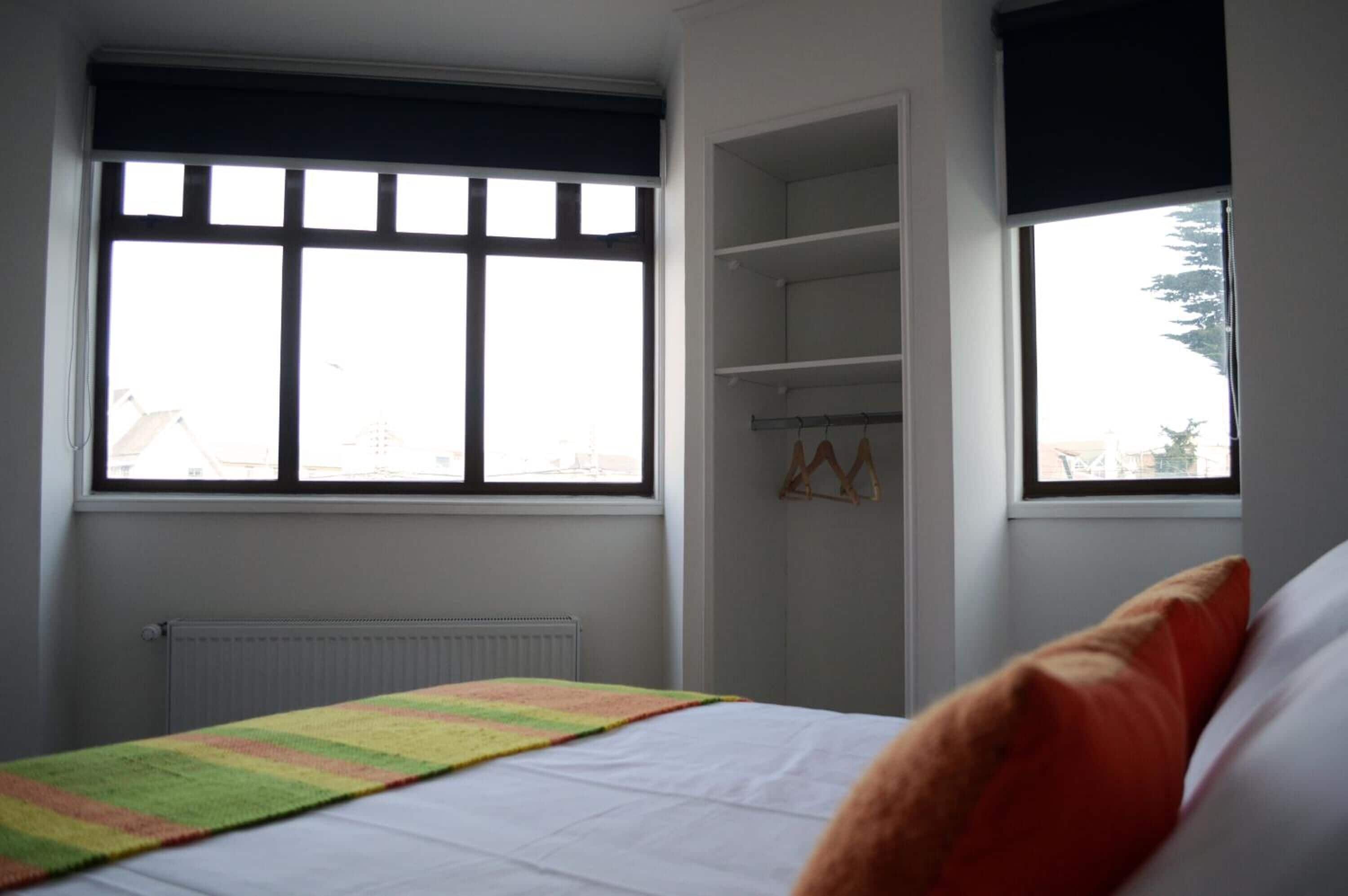 A bedroom with a bed, a window, a radiator, and a wardrobe.