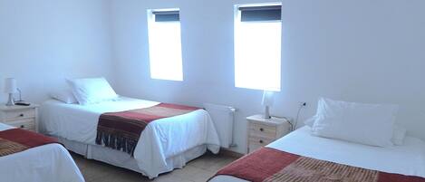 A hotel room with two beds, a window, a nightstand, and a lamp.