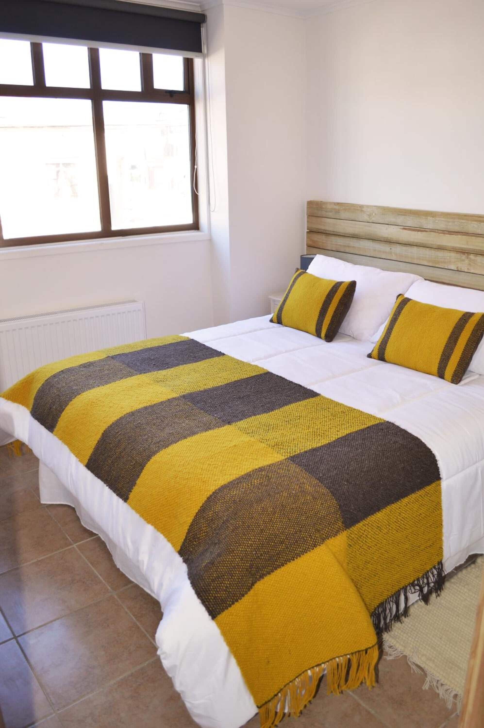 A bedroom with a bed, a window, and a radiator.