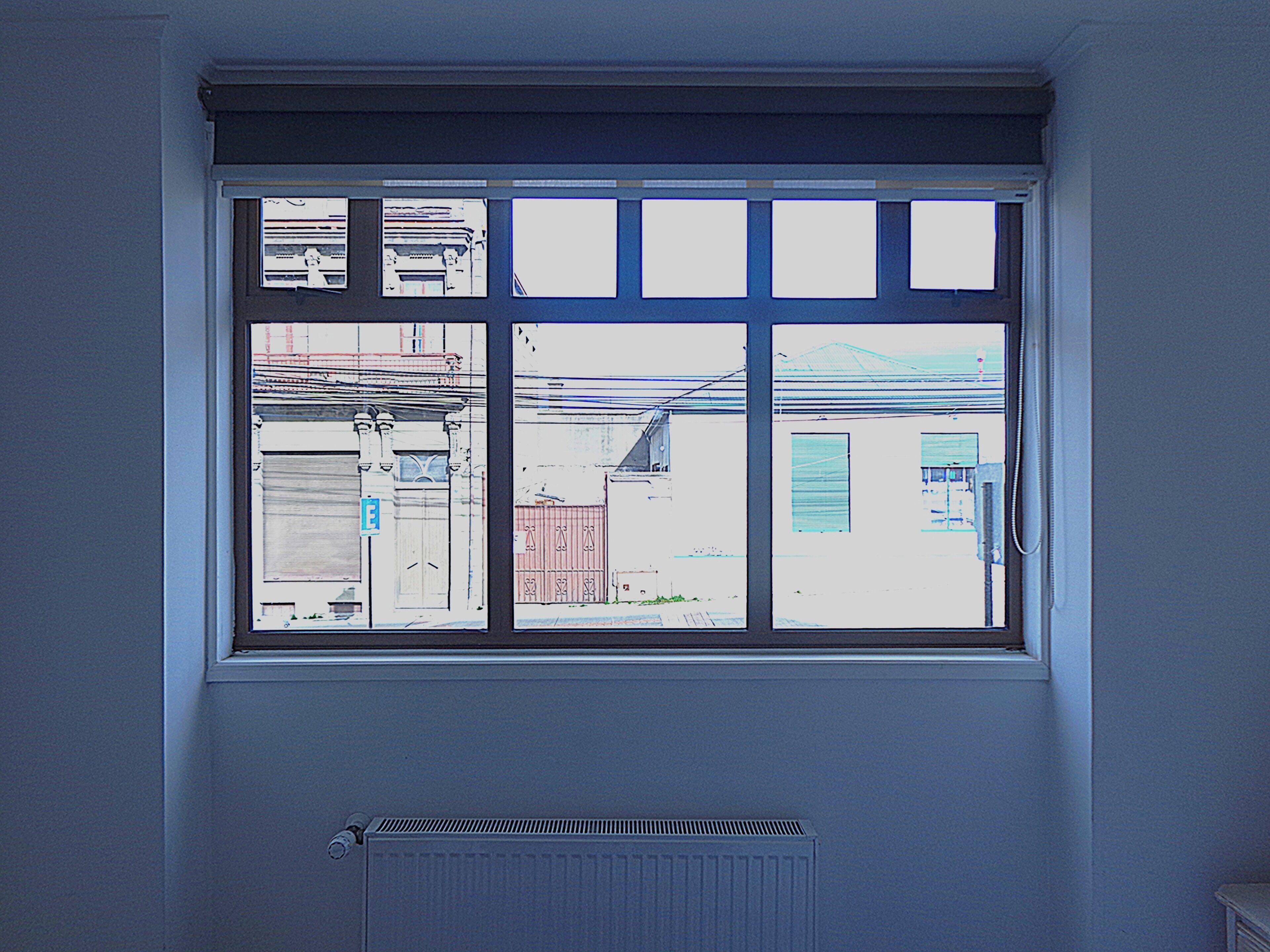 Una ventana con vista a edificios y un radiador debajo.