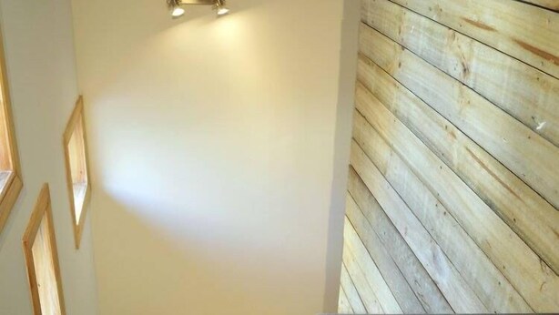 A staircase with wooden steps and a handrail, leading to a room with a wooden wall and a light fixture. - Apart Hotel Endurance (Punta Arenas)