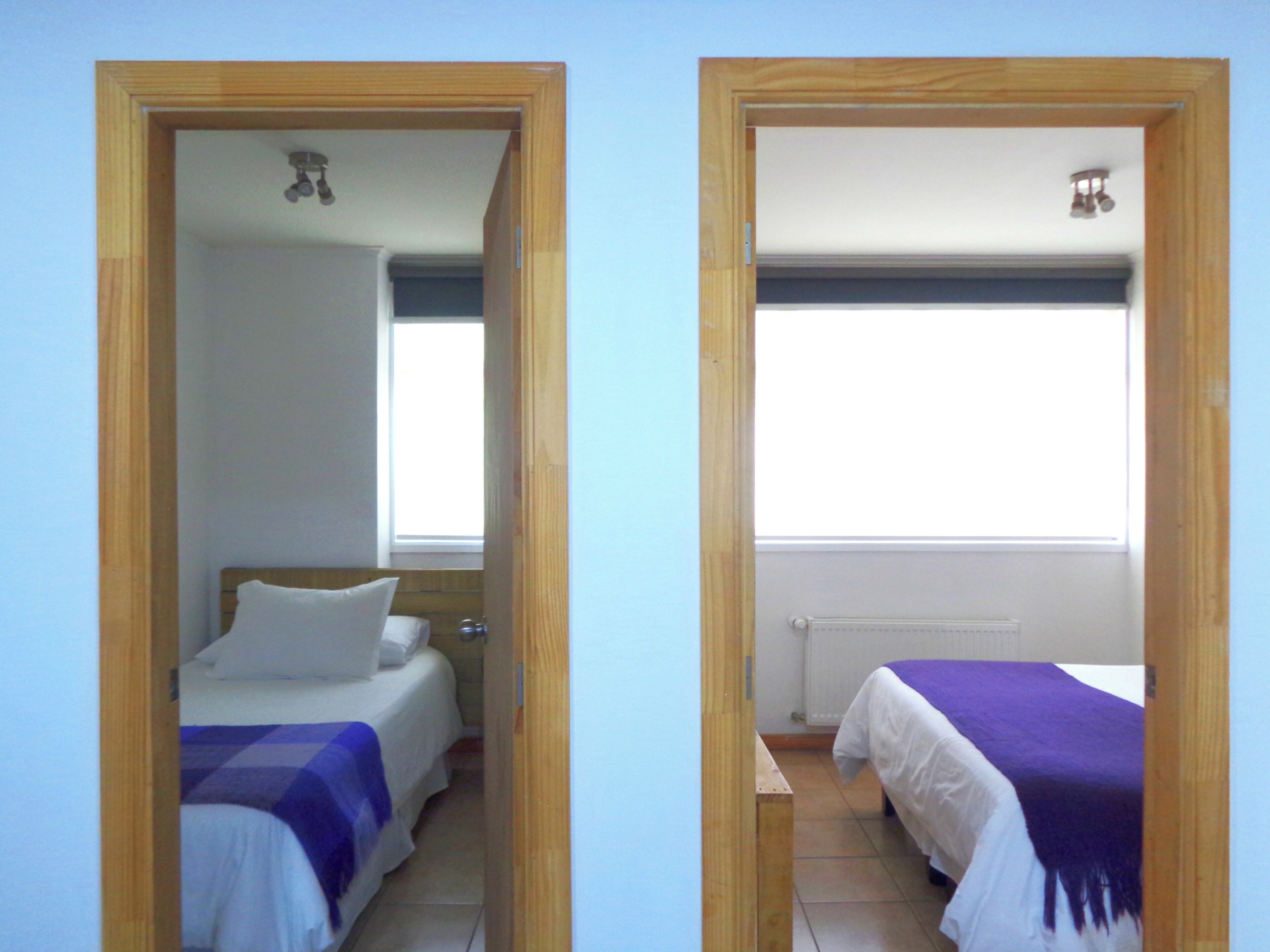 Two adjacent rooms with beds, a window, and a radiator.