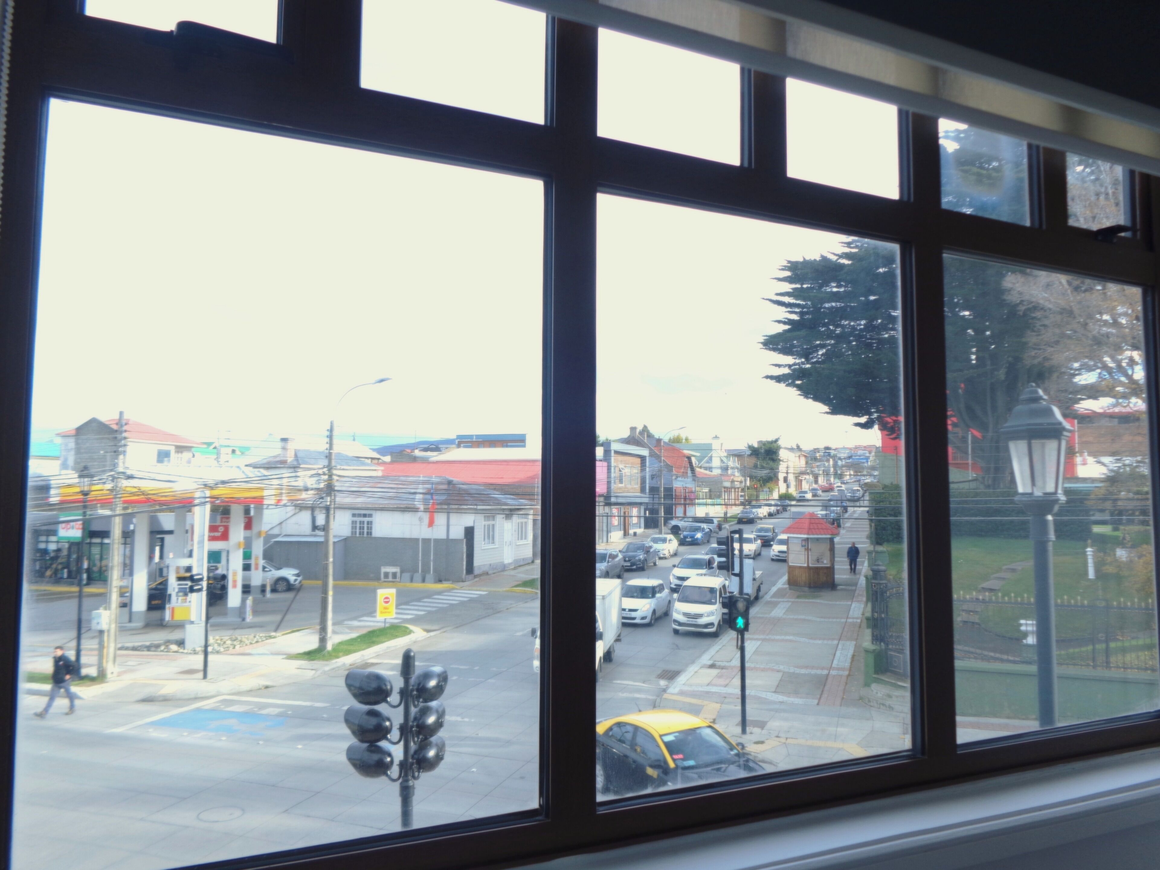 A view through a window with a street scene, including buildings, cars, and a traffic light.