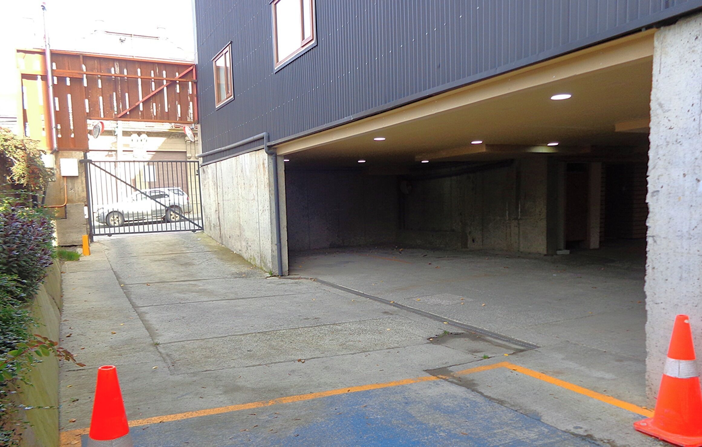 Un edificio con entrada para coches, un camino de hormigón y un vehículo estacionado.