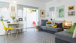 Un salon moderne avec un canapé gris, une table à manger avec des chaises et un sol à motifs.