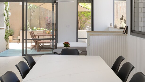Een moderne eethoek met een witte marmeren tafel, zwarte stoelen en uitzicht op het buitenterras.