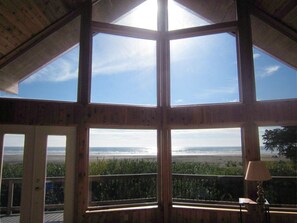 Habitació amb grans finestres que ofereixen vista a la platja i a l'oceà.