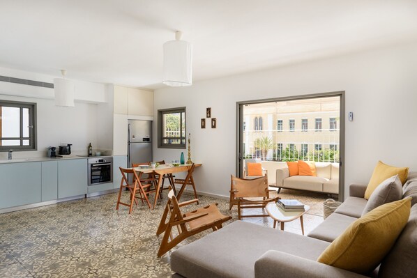 Un espacio habitable moderno con comedor, cocina y sofá con cojines.