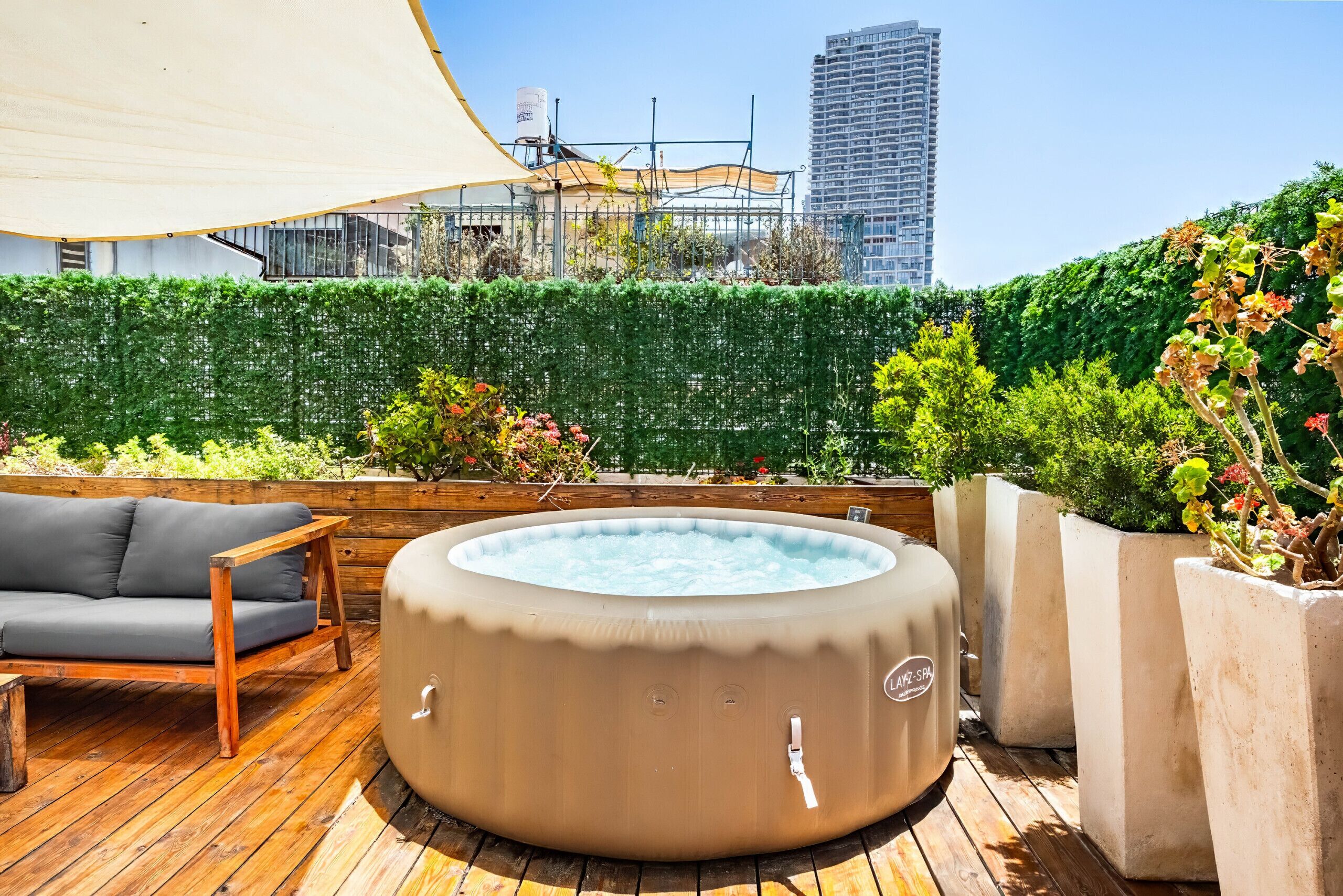 Un patio en la azotea con jacuzzi, terraza de madera y vista panorámica de la ciudad.