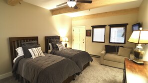 Une chambre avec deux lits, un canapé et un ventilateur de plafond.