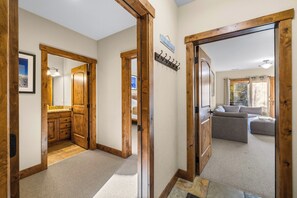 A hallway with wooden doors leading to a bedroom and a living area.