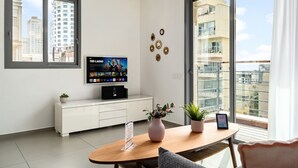 Un salon moderne doté d’un téléviseur à écran plat, d’un meuble blanc, d’une table en bois et d’un balcon offrant une vue sur la ville.