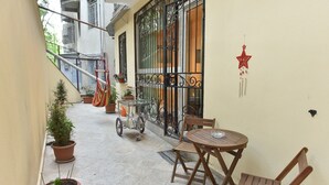 A narrow outdoor corridor with a small table and chairs, potted plants, and a metal gate. - Apartment in old Tbilisi (Dzveli Tbilisi)