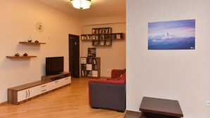 A living room with a flat-screen TV, a red sofa, a bookshelf, and a painting on the wall. - Apartment in old Tbilisi (Dzveli Tbilisi)