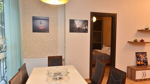A dining area with a table, chairs, and wall-mounted artwork. - Apartment in old Tbilisi (Dzveli Tbilisi)