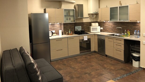 A modern kitchen with a Bosch refrigerator, a microwave, a stove, and wooden cabinets. - Apartment in old Tbilisi (Dzveli Tbilisi)