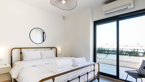 A modern bedroom with a large bed, a round mirror, a bedside table, and a view of the city through a large window.