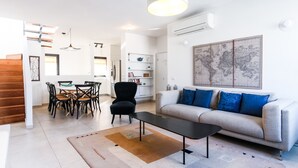 A modern living room with a sofa, coffee table, and dining area with chairs.