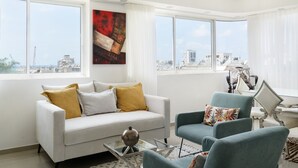 A modern living room with a sofa, armchairs, and a glass coffee table. - Penthouse with Terrace & Panoramic View by FeelHome (Tel Aviv - Jaffa)