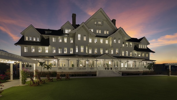 A large, multi-story house with a covered patio area, multiple windows, and a well-maintained lawn. - Belleview Inn (Belleair)