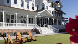 A large white house with multiple stories, a porch, and a well-maintained lawn. - Belleview Inn (Belleair)