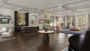 A spacious living area with a central round table, a reception desk, and a seating area with sofas and chairs. - Belleview Inn (Belleair)