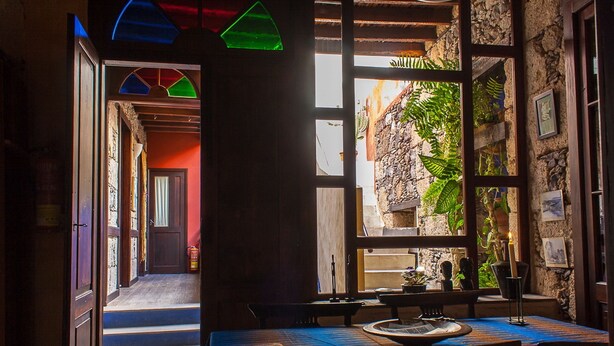 An interior with a dining area, stone walls, and a view of the outside. - Casa Luna (Agaete)