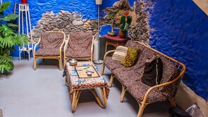 A cozy outdoor seating area with wicker furniture and a patterned tablecloth. - Casa Luna (Agaete)