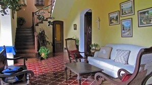 A living room with a patterned red and white floor, a white sofa, a wooden coffee table, and a wicker chair.