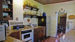 A kitchen with a stove, oven, refrigerator, and a dining area with a table and chairs.