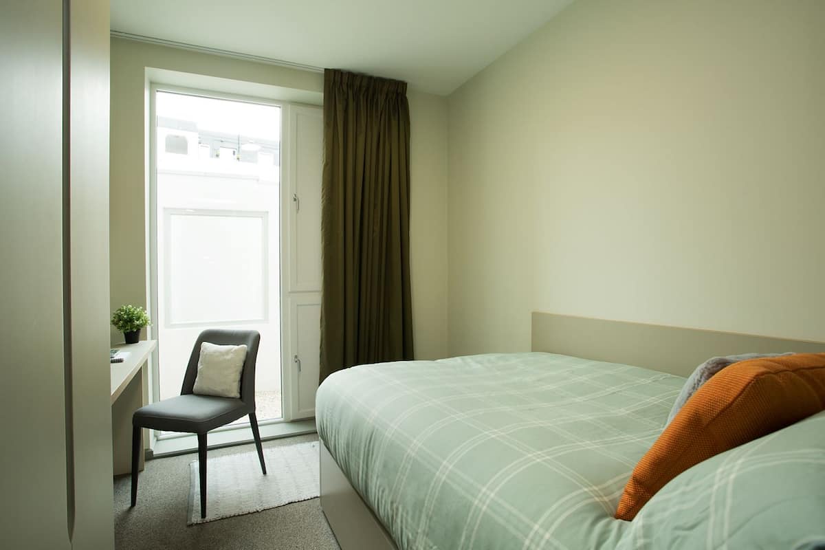A hotel room with a bed, a desk, and a chair.