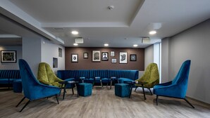 Un área de estar moderna con asientos azules, suelo de madera y cuadros en las paredes.