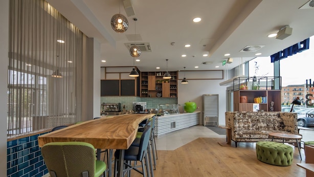 Una cocina moderna con barra, taburetes de madera y una manzana verde grande como adorno central.