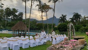 Una ceremonia de boda al aire libre con sillas blancas y un altar decorado.