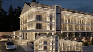 Un hôtel à plusieurs étages, doté d’une façade symétrique, de balcons et d’un espace extérieur couvert aménagé avec des sièges.
