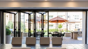 An indoor patio area with glass doors leading to an outdoor seating area. - Bluebird Suites in Silicon Valley (San Jose)