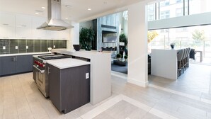 A modern kitchen with a central island, built-in oven, and a large window providing a view of the outdoors. - Bluebird Suites in Silicon Valley (San Jose)