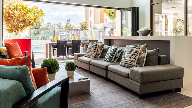 A modern living room with a grey sofa, red and green chairs, and a small coffee table. - Bluebird Suites in Silicon Valley (San Jose)