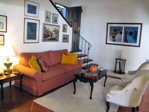 A living room with a sofa, armchair, coffee table, and a staircase. - Casita Jazmin (Antigua Guatemala)