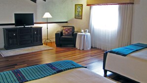 A room with two beds, a television on a cabinet, a lamp, and a painting on the wall. - Casita Jazmin (Antigua Guatemala)
