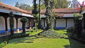 A courtyard with a tiled roof, surrounded by greenery and a well-maintained lawn. - Casita Jazmin (Antigua Guatemala)