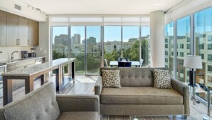 Un appartement moderne doté d’une cuisine, d’un canapé et d’un coin repas offrant une vue sur la ville.