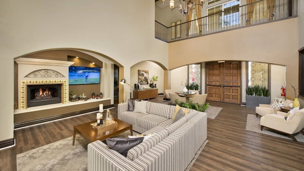 A spacious living room with a fireplace, a large sofa, a coffee table, and a TV. There is a balcony with a railing and a chandelier. - Bluebird Suites in Santa Clara (Santa Clara)