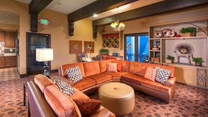 A spacious living area with a large sectional sofa, a round ottoman, and a chandelier. - Bluebird Suites in Santa Clara (Santa Clara)