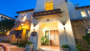 A two-story building with a flat roof, a central entrance with a door, and a large window above the door. - Bluebird Suites in Santa Clara (Santa Clara)
