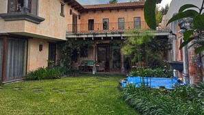 A two-story building with a balcony, a covered patio, and a well-maintained garden.