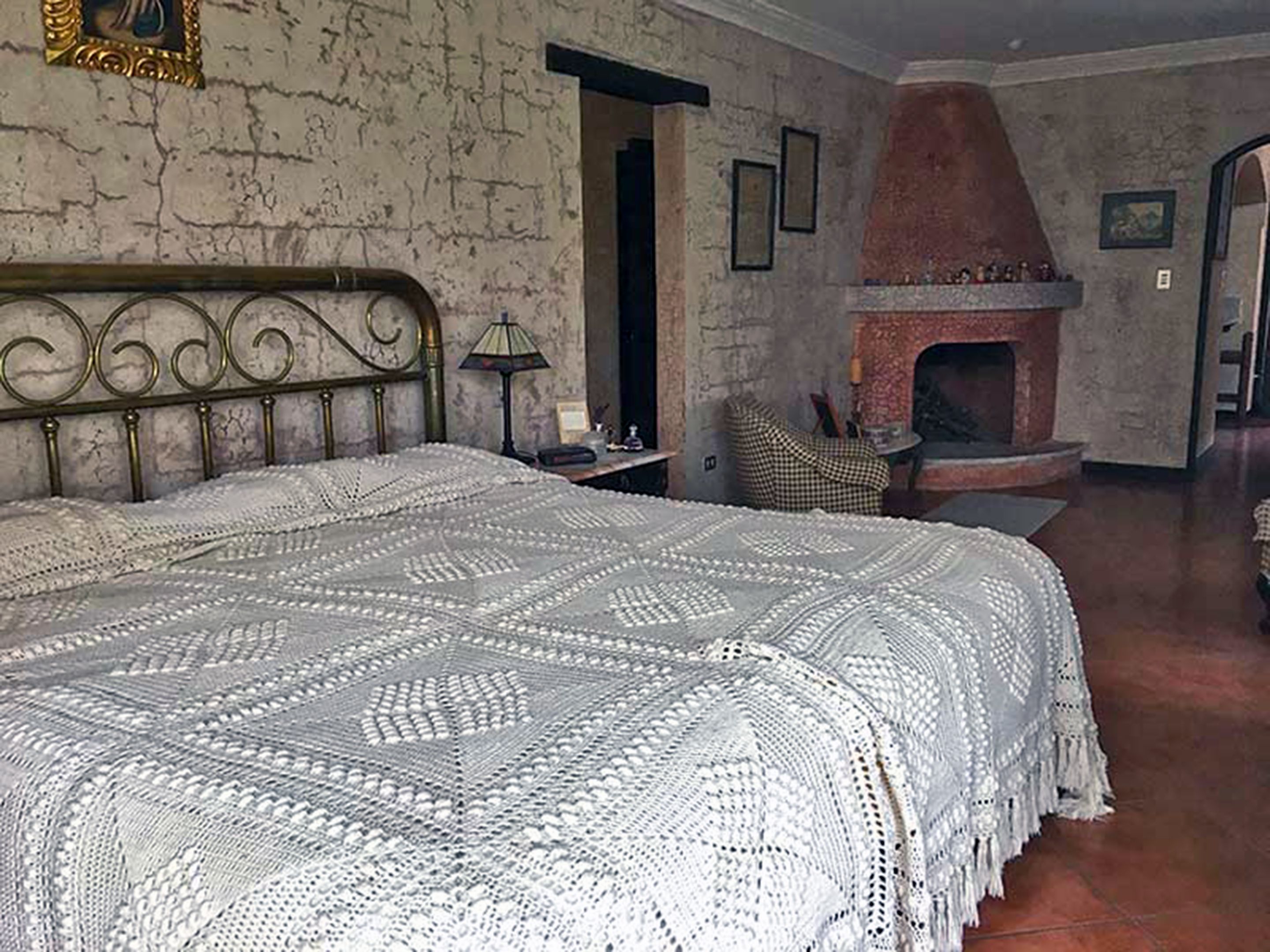 Una camera da letto con un letto grande, un camino e una poltrona a quadri.